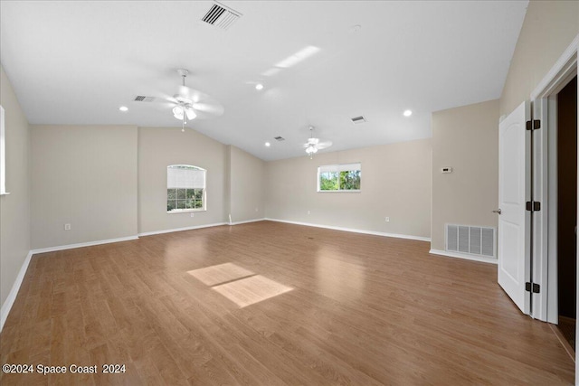 unfurnished living room with a wealth of natural light, ceiling fan, vaulted ceiling, and light wood-type flooring