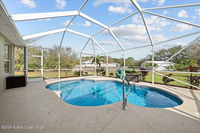 view of pool with a patio, glass enclosure, and a lawn