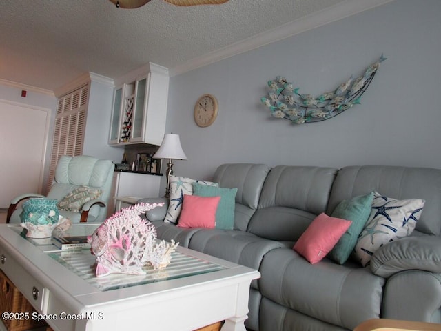 living room with crown molding, ceiling fan, and a textured ceiling