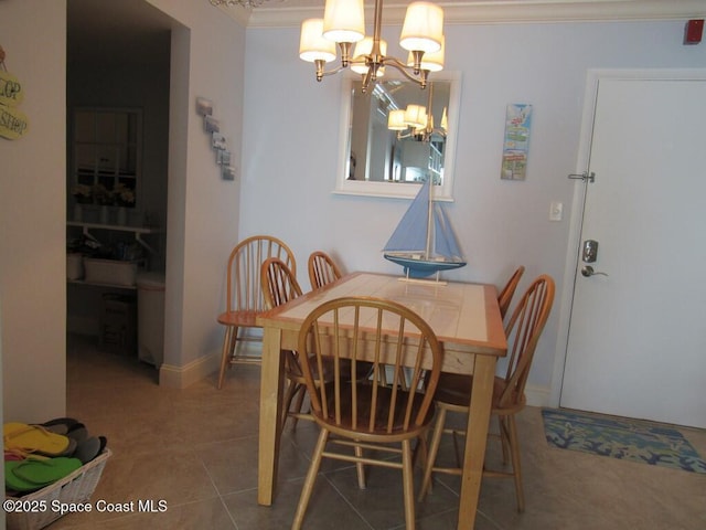 dining area with tile patterned flooring, crown molding, and a chandelier