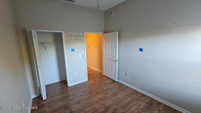 unfurnished bedroom featuring a closet, a towering ceiling, and hardwood / wood-style floors