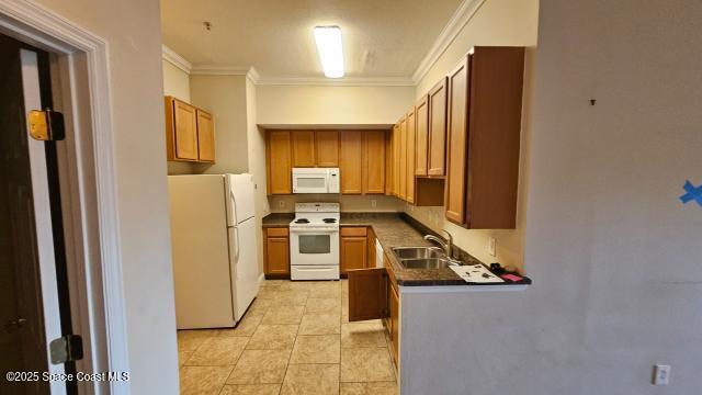 kitchen featuring white appliances, sink, light tile patterned floors, and ornamental molding