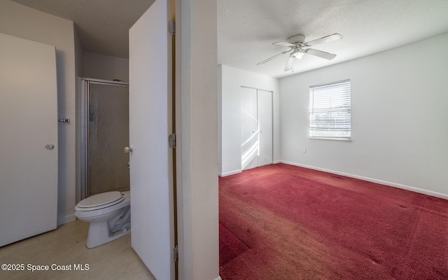 interior space featuring toilet, ceiling fan, a textured ceiling, and an enclosed shower