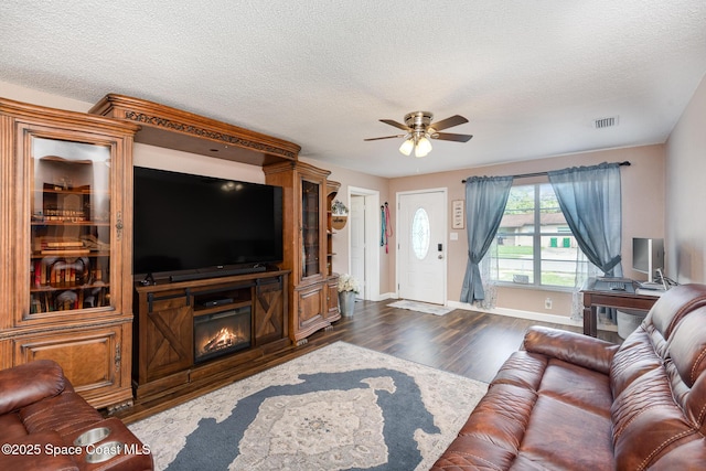 living room with a textured ceiling, dark hardwood / wood-style flooring, and ceiling fan