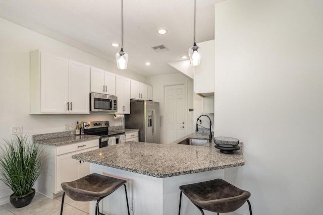 kitchen with white cabinetry, sink, kitchen peninsula, a breakfast bar area, and appliances with stainless steel finishes