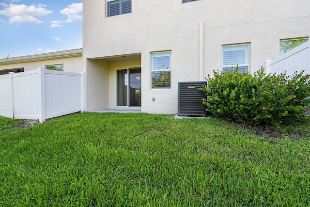 back of property featuring a lawn and central air condition unit