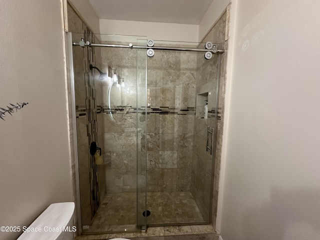 bathroom featuring toilet and a shower with door