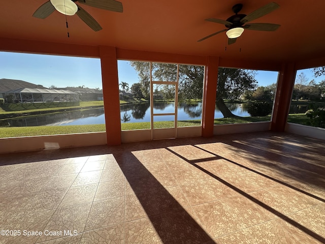 unfurnished sunroom with ceiling fan, a healthy amount of sunlight, and a water view