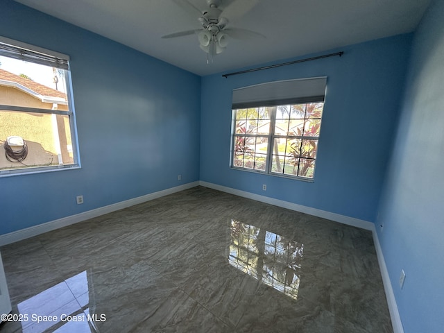 empty room featuring ceiling fan and plenty of natural light