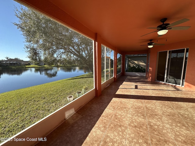 unfurnished sunroom featuring ceiling fan and a water view