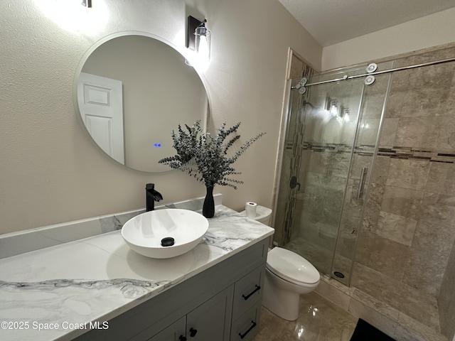 bathroom with toilet, vanity, and a shower with door