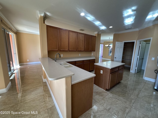 kitchen featuring an inviting chandelier, kitchen peninsula, hanging light fixtures, crown molding, and sink