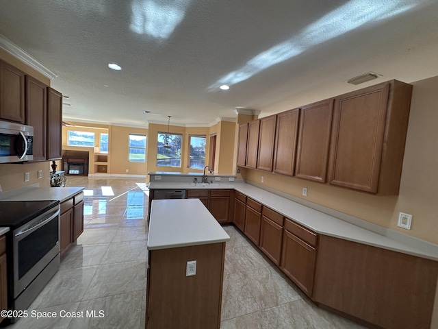 kitchen with decorative light fixtures, kitchen peninsula, sink, crown molding, and appliances with stainless steel finishes