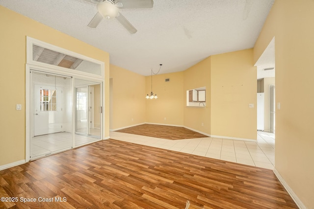 unfurnished room with a textured ceiling, ceiling fan with notable chandelier, and light wood-type flooring