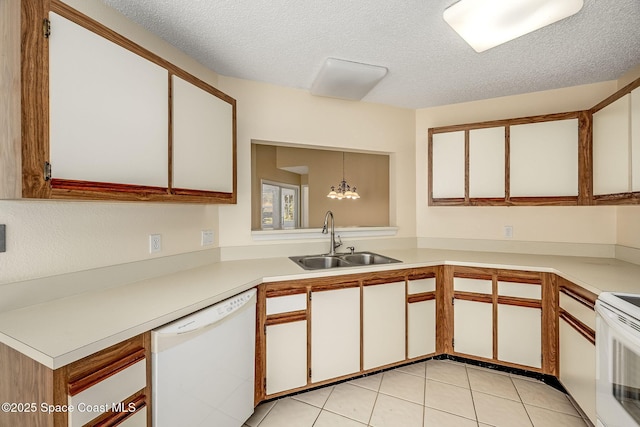 kitchen featuring white appliances, white cabinetry, hanging light fixtures, and sink