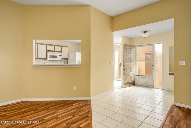 spare room with a textured ceiling and light hardwood / wood-style flooring