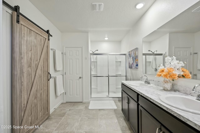 bathroom with a textured ceiling, vanity, and an enclosed shower