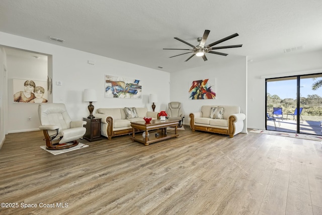 living room featuring ceiling fan, light hardwood / wood-style floors, and a textured ceiling