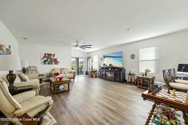 living room with hardwood / wood-style floors, a textured ceiling, and ceiling fan