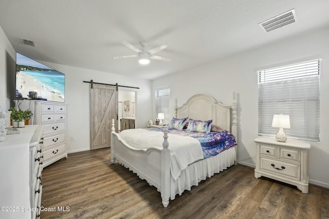 bedroom with dark hardwood / wood-style flooring, a barn door, ceiling fan, and connected bathroom