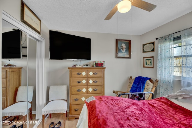 bedroom with ceiling fan, light hardwood / wood-style floors, and a textured ceiling