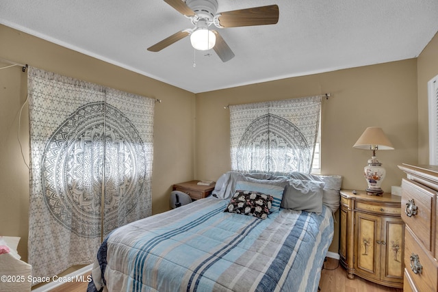 bedroom with ceiling fan, wood-type flooring, and a textured ceiling