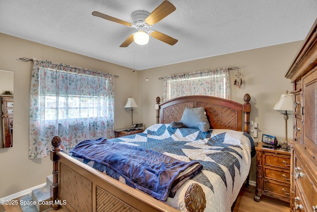 bedroom featuring ceiling fan, light hardwood / wood-style floors, and a textured ceiling