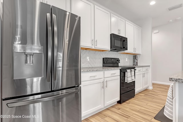 kitchen featuring black appliances, white cabinets, light hardwood / wood-style flooring, decorative backsplash, and light stone counters