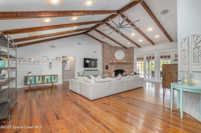 living room with beam ceiling, ceiling fan, high vaulted ceiling, light hardwood / wood-style floors, and a fireplace