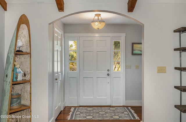 foyer entrance with a notable chandelier, dark hardwood / wood-style floors, a healthy amount of sunlight, and beamed ceiling