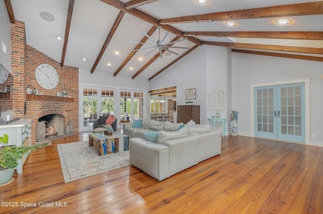 living room featuring french doors, light wood-type flooring, a brick fireplace, and ceiling fan