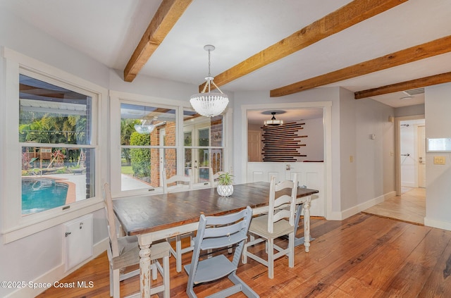 dining room with beamed ceiling and light hardwood / wood-style floors