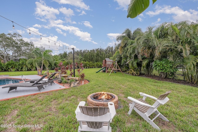 view of yard with a playground, a patio area, and a fire pit