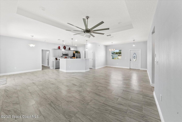 unfurnished living room featuring ceiling fan and a textured ceiling