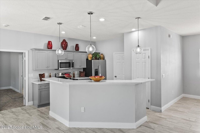 kitchen featuring appliances with stainless steel finishes, gray cabinets, decorative light fixtures, and a kitchen island