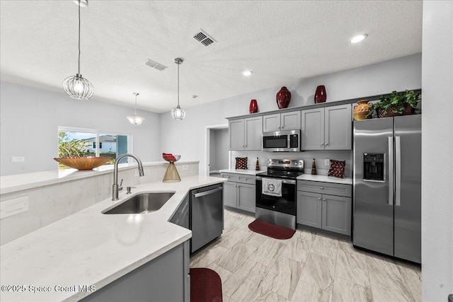 kitchen featuring gray cabinetry, decorative light fixtures, sink, and appliances with stainless steel finishes