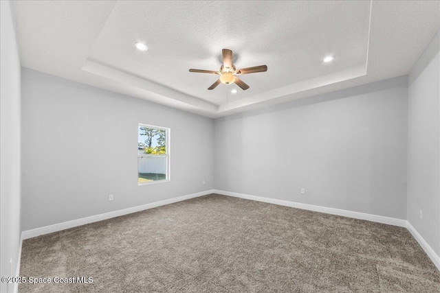 carpeted empty room featuring a textured ceiling, a tray ceiling, and ceiling fan