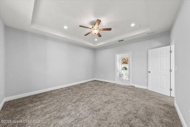 carpeted empty room with ceiling fan, a raised ceiling, and a textured ceiling