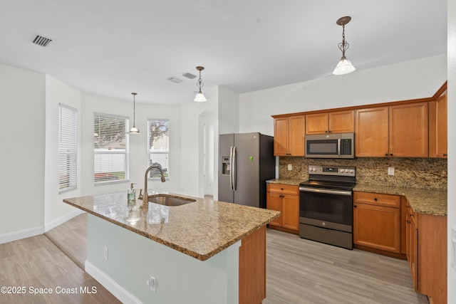 kitchen featuring sink, light stone countertops, hanging light fixtures, and appliances with stainless steel finishes