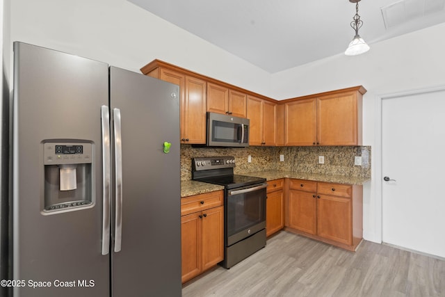 kitchen featuring appliances with stainless steel finishes, pendant lighting, tasteful backsplash, light hardwood / wood-style floors, and light stone countertops