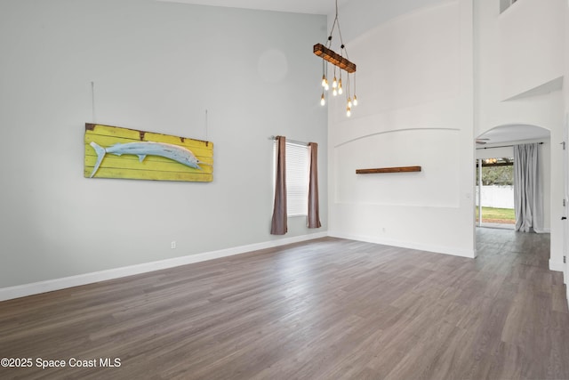 unfurnished living room with dark hardwood / wood-style flooring and high vaulted ceiling