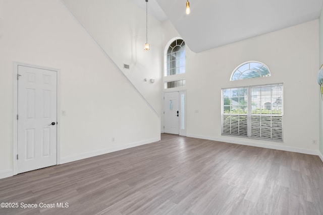 unfurnished living room featuring high vaulted ceiling and hardwood / wood-style floors