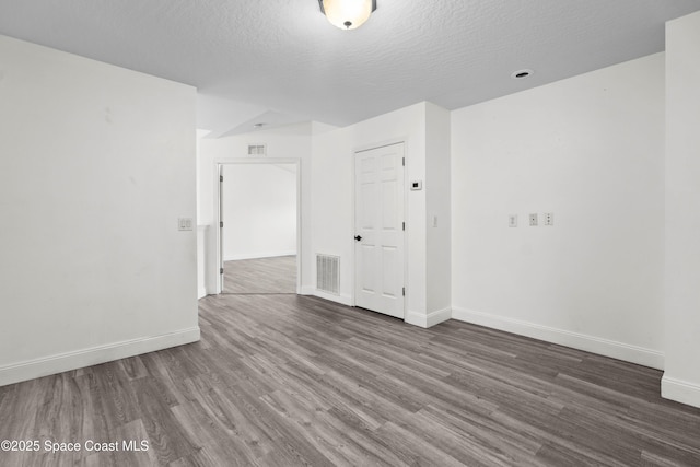 empty room with dark hardwood / wood-style floors and a textured ceiling