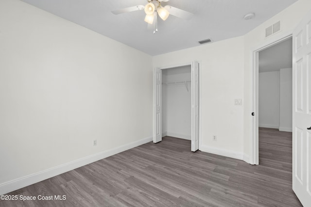 unfurnished bedroom with ceiling fan, dark hardwood / wood-style floors, and a closet