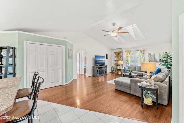 living room featuring ceiling fan, light tile patterned floors, and vaulted ceiling