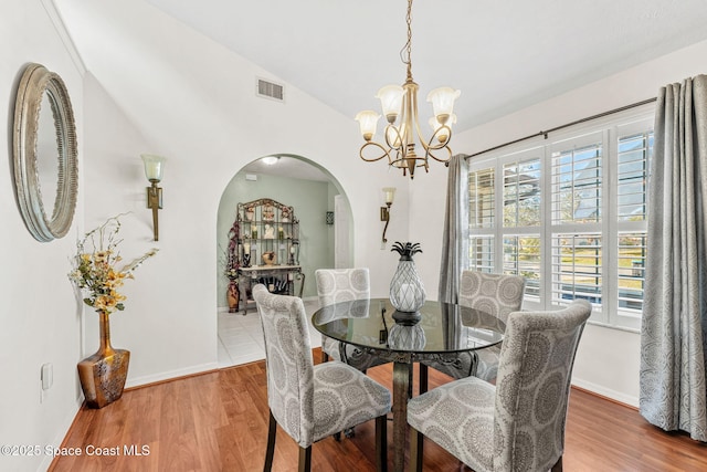 dining room featuring a chandelier, hardwood / wood-style floors, and lofted ceiling