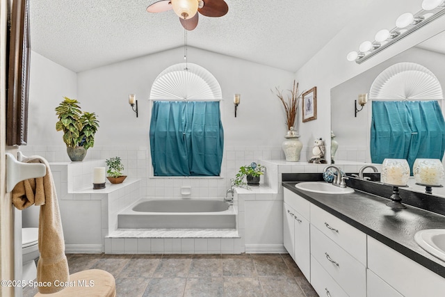 bathroom with a bathing tub, a textured ceiling, vanity, and lofted ceiling