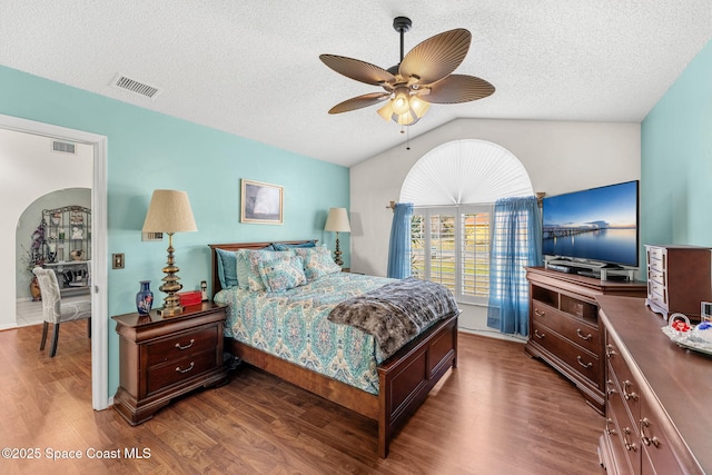 bedroom with a textured ceiling, ceiling fan, dark hardwood / wood-style floors, and vaulted ceiling