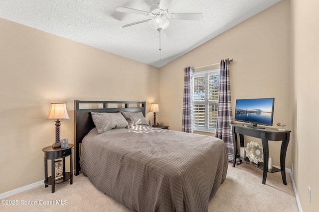 bedroom with ceiling fan, light colored carpet, lofted ceiling, and a textured ceiling