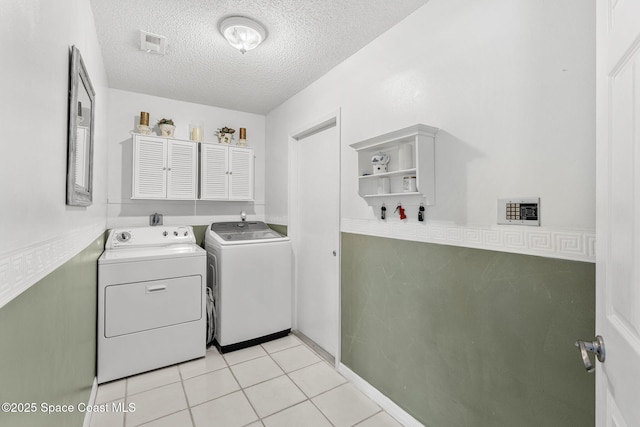 washroom with independent washer and dryer, a textured ceiling, and light tile patterned floors